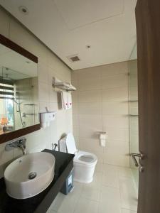 a bathroom with a sink and a toilet and a mirror at Apec Mandala Hotel Tuy Hoà in Tuy Hoa