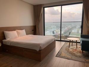 Apec Mandala Hotel Tuy Hoà في توي هوا: غرفة نوم بسرير ونافذة كبيرة