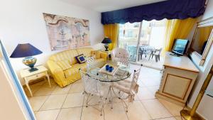 ein Wohnzimmer mit einem Glastisch und einer gelben Couch in der Unterkunft Résidence Victoria Beach - 2 Pièces pour 4 Personnes 954 in Menton