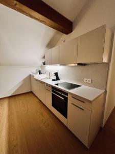 a kitchen with white cabinets and a sink and a stove at Ferienwohnung zum Kalmbach in Kochel +16 photos