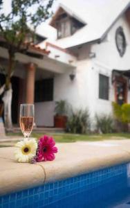 a glass of wine and flowers on the edge of a swimming pool at Linda casa céntrica c/alberca y jacuzzi in Xochitepec