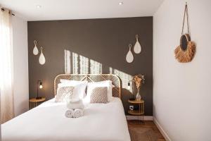 um quarto com uma cama com lençóis brancos e almofadas em L'Exotique - Gare/centre, lumineux, spacieux, neuf em Châteauroux