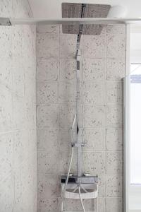 a shower in a bathroom with white tiled walls at L'Exotique - Gare/centre, lumineux, spacieux, neuf in Châteauroux