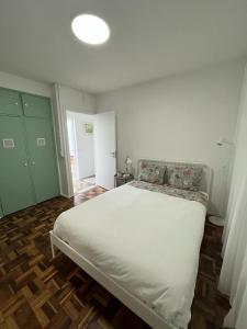 a bedroom with a white bed and a green door at Alto Guest room in Lousã