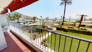 d'un balcon avec vue sur la plage et les palmiers. dans l'établissement Résidence Le Marly - Studio pour 4 Personnes 344, à Menton