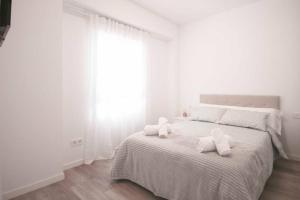 a white bedroom with a bed with two pillows on it at Precioso apartamento a 10 min de la playa in Castellón de la Plana