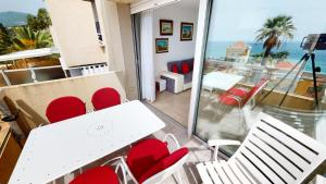 uma varanda com uma mesa e cadeiras brancas e o oceano em Résidence Les Terrasses De La Mer - 2 Pièces pour 2 Personnes 024 em Menton