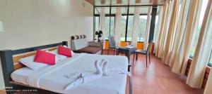 1 dormitorio con 1 cama con sábanas blancas y almohadas rojas en Estet stay with pool en Madikeri