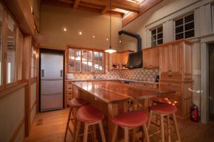 una cocina con una gran isla de madera con taburetes rojos en [Hida Takayama] Kiyomi-sou- - Vacation STAY 33671v, en Takayama