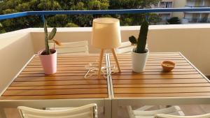 einen Tisch auf einem Balkon mit Topfpflanzen und einer Lampe in der Unterkunft Résidence Les Rivages Du Parc - 2 Pièces pour 4 Personnes 454 in Menton