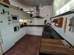 una cucina con armadi bianchi e piano cottura di Casa Alborada a Cercedilla