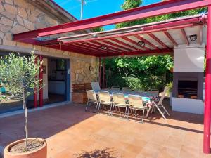 une pergola rouge avec une table et des chaises sur une terrasse dans l'établissement Casa Alborada, à Cercedilla