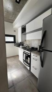 a kitchen with white cabinets and a refrigerator at Las Marias Apart I in Necochea