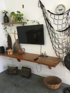 a flat screen tv on a wall with a shelf at Casa da Calmaria in Santa Cruz Cabrália