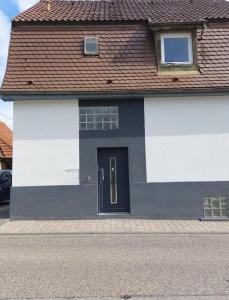a white house with a black door on a street at Wohnen wie Zuhause in Abstatt