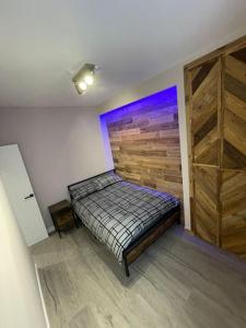 a bedroom with a bed and a wooden wall at 1bedroom ground floor apartment in Aberdeen