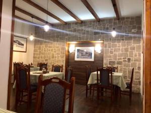 a dining room with tables and chairs and a stone wall at Restaurant & Apartments JUG in Sutomore