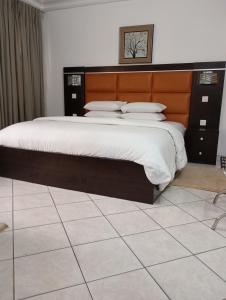 a bedroom with a large bed with a wooden headboard at Cata Apartment Hotel And Spa in Ikeja