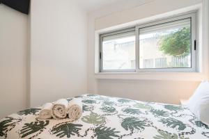1 dormitorio con 1 cama con toallas y ventana en Moreira Terrace, en Oporto