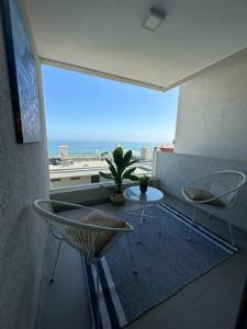 uma varanda com uma mesa e cadeiras e uma grande janela em Depto. frente al Mar - Costa Higuerillas em Concón
