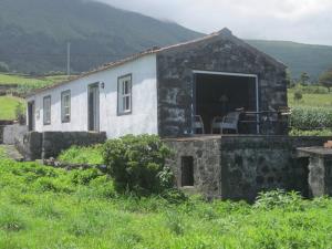 a stone house with a porch and a patio at Casa dos Vimes - mar e céu in São Roque do Pico