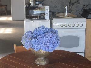 a vase of blue flowers sitting on a table at Casa dos Vimes - mar e céu in São Roque do Pico