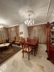 sala de estar con mesa de madera y sillas en Comfortable family apt - 1002 en Amán
