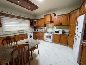 una cocina con armarios de madera y una mesa con sillas. en Comfortable family apt - 1002 en Amán