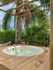 una bañera en una terraza de madera con una palmera en Casa de Temporada em Capitólio (Charme e Aconchego) en Capitólio