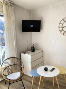 uma sala de estar com uma mesa e uma televisão na parede em Résidence Montcalm C - Studio pour 2 Personnes 004 em Aix-les-Bains