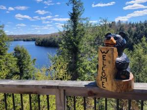 a statue of a bear holding a sign that reads new job at The Bear Cave Cottage at Little Kennisis Lake in Algonquin Highlands