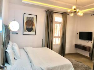 a bedroom with a white bed and a television at Elegant 3 Bedroom Apartment in Lekki
