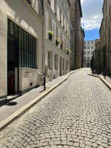 an empty cobblestone street in a city with buildings at Loft 50m2 entre la Seine et le Panthéon in Paris