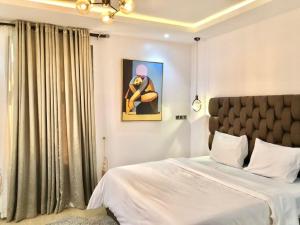 a bedroom with a bed and a painting on the wall at Elegant 3 Bedroom Apartment in Lekki