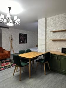 une salle à manger avec une table en bois et des chaises vertes dans l'établissement Sinay Hotel & Restaurant, à Chechel'nyk