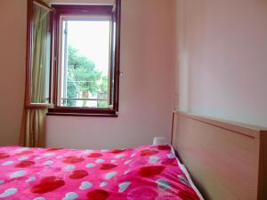 una camera da letto con un letto con un piumone rosa e una finestra di SE043 - Senigallia, nuovo trilocale accessoriato a 100 mt dal mare a Senigallia