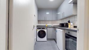 a white kitchen with a washing machine in it at Lovely 1 double bed Studio in Marylebone in London