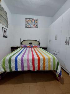 a bedroom with a bed with a colorful striped blanket at Cantinho das Olandas in Olinda