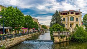 a river in a city with a bridge and buildings at La Collégiale in LʼIsle-sur-la-Sorgue