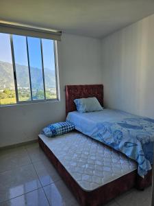 a bed in a room with a large window at Apartamento en Ibagué - Varsovia in Ibagué