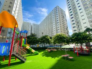 a playground with a slide in a park with tall buildings at Homefort at Shore Residences in Manila