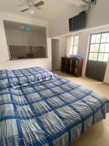 Schlafzimmer mit einem Bett mit einer blauen und weißen Bettdecke in der Unterkunft Estudio en el centro de Coatepec in Coatepec