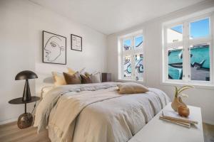 a white bedroom with a large bed and two windows at Central Apartment with Balcony, Self-check in & Private entrance in Bergen