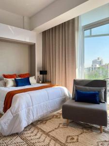 a bedroom with a bed and a chair and a window at Chic 1BR Loft in the Heart of Roma Norte in Mexico City