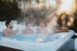 un grupo de personas en una bañera de hidromasaje con bebidas en Chalet Red Deer Spa at Fiddler Lake, en Mille-Isles