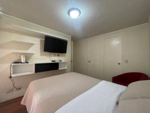 1 dormitorio con 1 cama blanca y TV de pantalla plana en Panoramic Aparment San Miguel en Lima