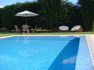 a swimming pool with an umbrella and a table and chairs at Quinta de Santa Clara in Ponta Delgada