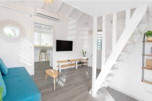 a white living room with a blue couch and a tv at Ticase, charmante maisonnette idéalement située in Saint Martin