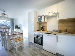 eine Küche mit weißen Schränken und einem kleinen Tisch mit einer Theke in der Unterkunft Appartement Neuf pour 6, Parking Gratuit, Skis et Accès Pistes en 5min - FR-1-695-4 in Germ