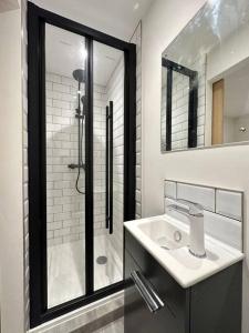y baño blanco con lavabo y ducha. en Modern apartment in high street location. en Midsomer Norton